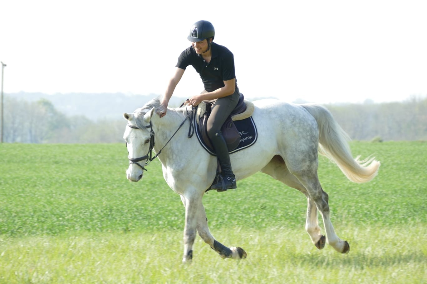 Anis riding a grey horse outdoors